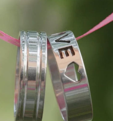 silver love rings hanging on a pink ribbon 