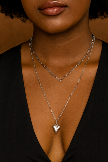 Woman wearing layered silver necklaces, including a heart pendant