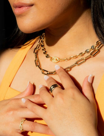 ChatGPT:

gold layered chain necklaces and gold rings on model’s hands