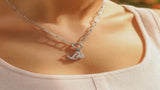 Silver stainless steel charm-holder necklace with anchor and sailboat pendants worn on the neck.