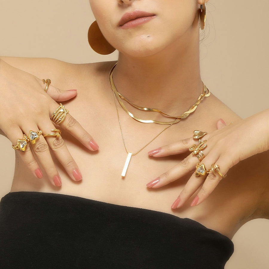 gold layered necklaces and multiple gold rings on model’s hands